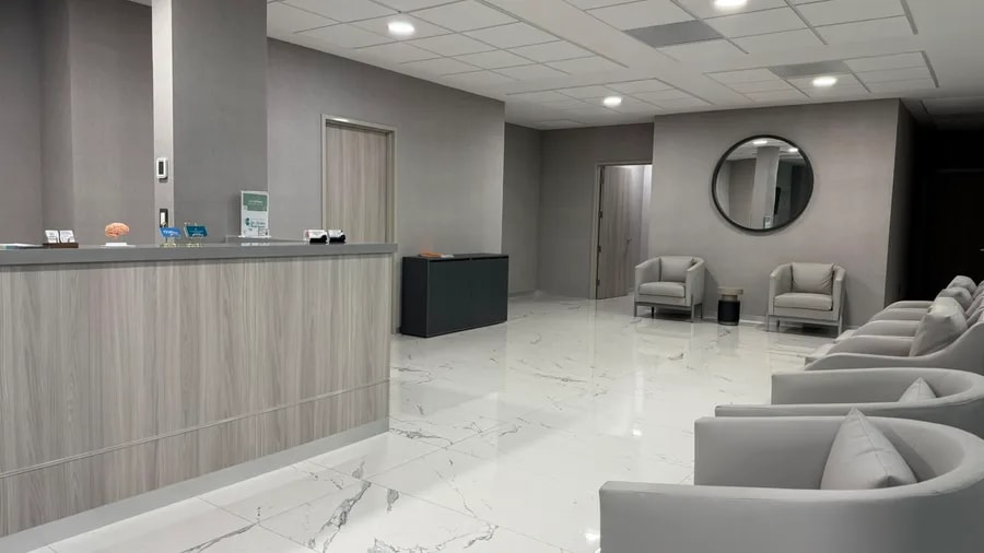 Sala de espera con sillones, piso de mármol y recepción