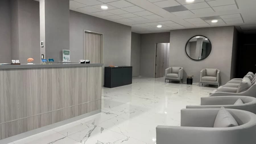 Sala de espera con sillones, piso de mármol y recepción